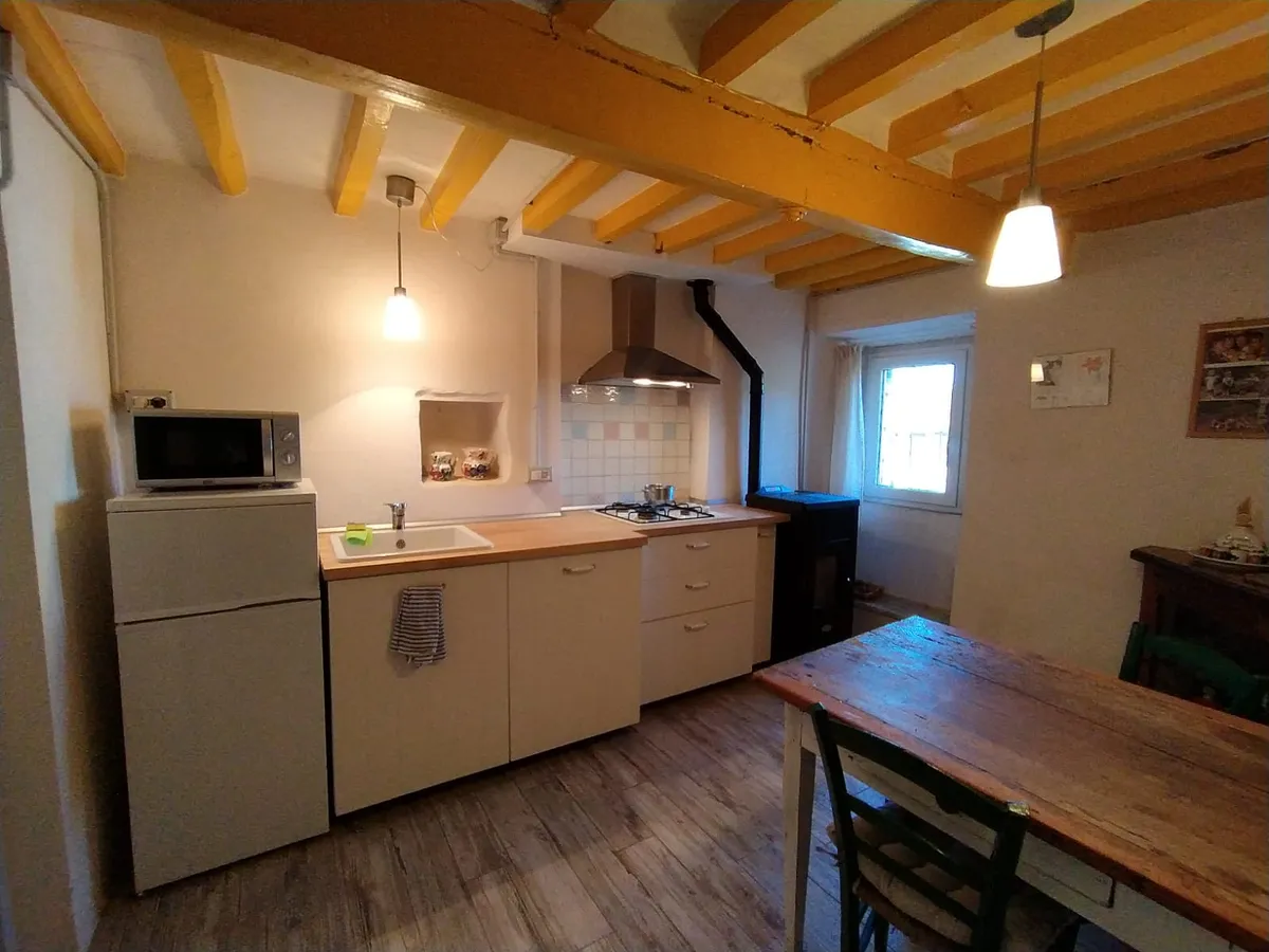 Cucina con travi gialle e stufa a legna